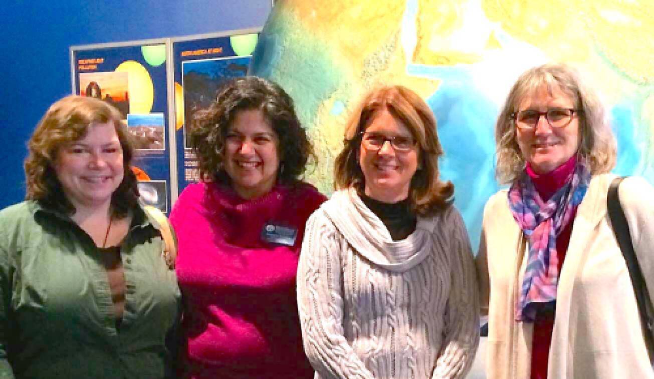 Four women in front of a large globe